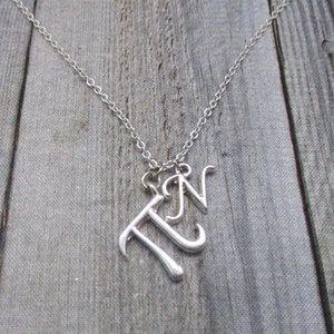 May include: A silver necklace with a charm that spells out "Pi" in cursive.