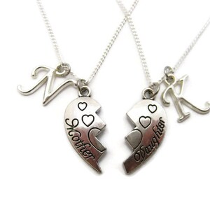 May include: Two silver necklaces with matching heart pendants that say "Mother" and "Daughter". Each necklace also has a silver letter charm.