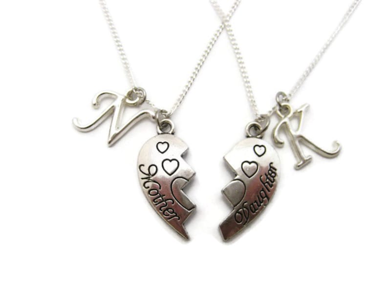 May include: Two silver necklaces with matching heart pendants that say "Mother" and "Daughter". Each necklace also has a silver letter charm.