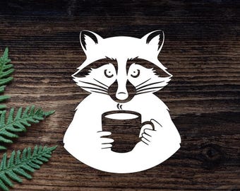 May include: A white silhouette of a raccoon holding a coffee mug. The raccoon is sitting on a brown wooden background.