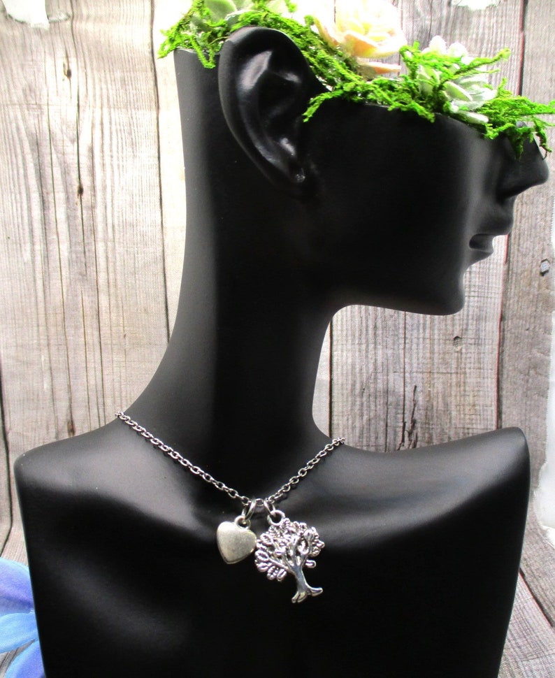 Puede incluir: Un collar de plata con un dije de &aacute;rbol y coraz&oacute;n. El collar est&aacute; en un busto de maniqu&iacute; negro.