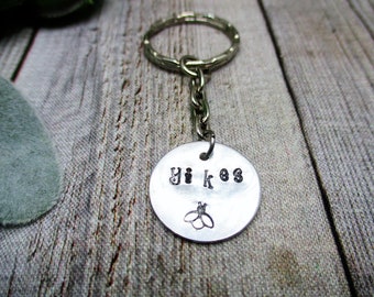 May include: Silver keychain with a round metal tag that says "Yiikos" with a small bee design.