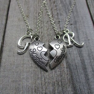 May include: Two silver necklaces with matching heart pendants that say "Mother" and "Daughter". Each necklace also has a letter charm, a "G" and an "R".