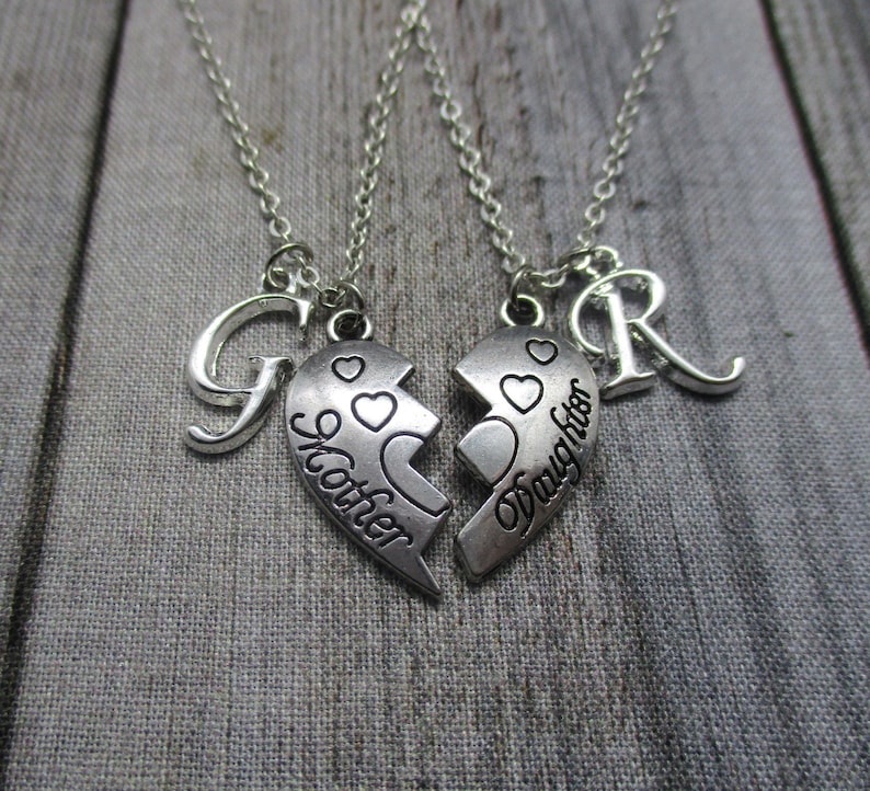 May include: Two silver necklaces with matching heart pendants that say "Mother" and "Daughter". Each necklace also has a letter charm, a "G" and an "R".