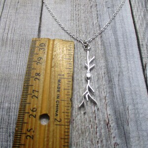 Puede incluir: Collar de plata con un delicado colgante de rama. El colgante mide aproximadamente 5 cm de largo y presenta un peque&ntilde;o cristal transparente.