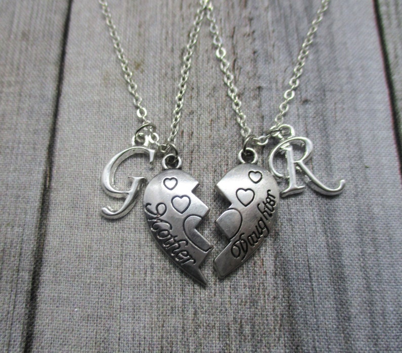 May include: Two silver necklaces with matching broken heart pendants. One pendant says "Sister" and the other says "Daughter". Each necklace has a letter charm, one is a "G" and the other is an "R".
