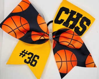 May include: Yellow and black cheer bow with a basketball pattern, the words "CHS" and "#36" in black glitter, and a rhinestone in the centre.