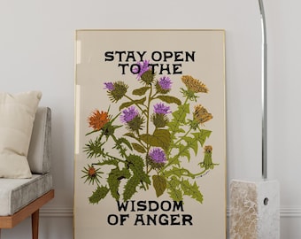 May include: A rectangular wall art print in a thin gold frame featuring a botanical illustration of green thistle plants with purple and orange flowers. The text STAY OPEN TO THE and WISDOM OF ANGER is printed in black block letters.