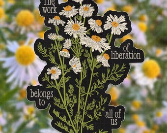 May include: A die-cut sticker featuring a black background with a botanical illustration of white chamomile flowers with yellow centers and green stems. The text reads: The work of liberation belongs to all of us, written in a white serif font.