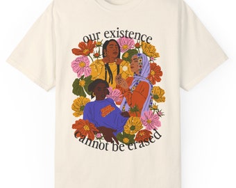Puede incluir: Una camiseta de color crema con un gráfico de tres mujeres de color rodeadas de flores. El texto "our existence cannot be erased" está impreso debajo del gráfico.