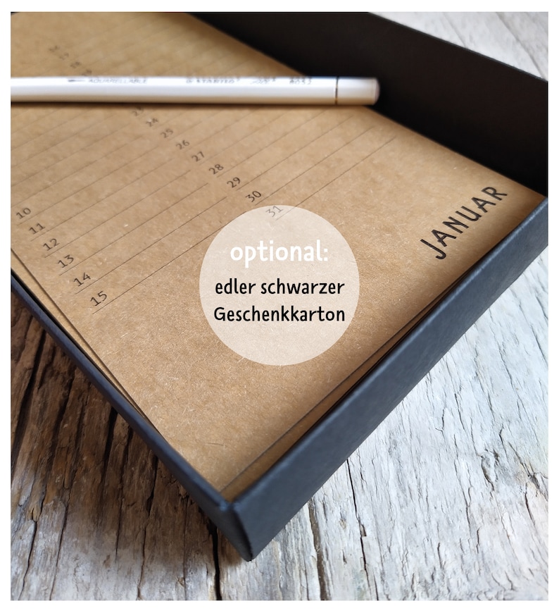 May include: A brown paper calendar with the month of January printed on it. The calendar is in a black box. The text "optional: edler schwarzer Geschenkkarton" is printed on the calendar.