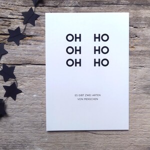 May include: A white rectangular greeting card featuring the black text OH HO, OH HO, OH HO arranged in two columns, with the German text ES GIBT ZWEI ARTEN VON MENSCHEN printed in smaller black capital letters at the bottom of the card.
