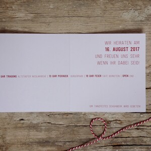 May include: A pink wedding invitation card with red text. The text reads "We are getting married on August 16, 2017 and we are very happy if you can be there!"  The card also includes details about the wedding ceremony, picnic, and reception.