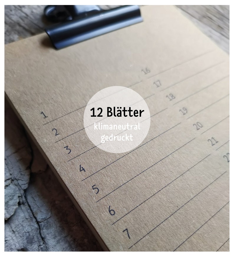 May include: A brown clipboard with a black clip at the top. The clipboard has 12 lined pages and the text "12 Bl&auml;tter klimaneutral gedruckt" is printed on the front.
