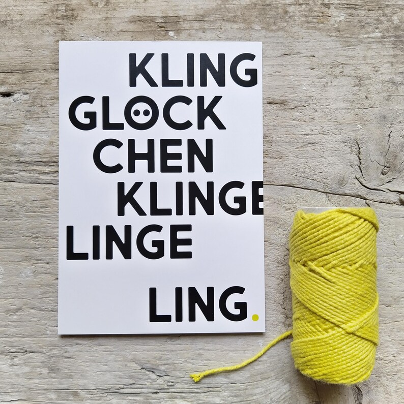 May include: A white rectangular card featuring black text that reads KLING GLOCK CHEN KLINGE LINGE LING with a small yellow dot. Next to the card is a spool of thick, bright yellow cord made of twisted fibers, with a loose end extending outward.