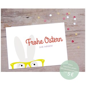 Peut inclure: Un lapin blanc portant des lunettes jaunes se cache derri&egrave;re une carte blanche. La carte est d&eacute;cor&eacute;e de l'inscription "Frohe Ostern" en rouge et "Ihr Hasen!" en noir. La carte a un fond vert clair avec une bordure blanche.