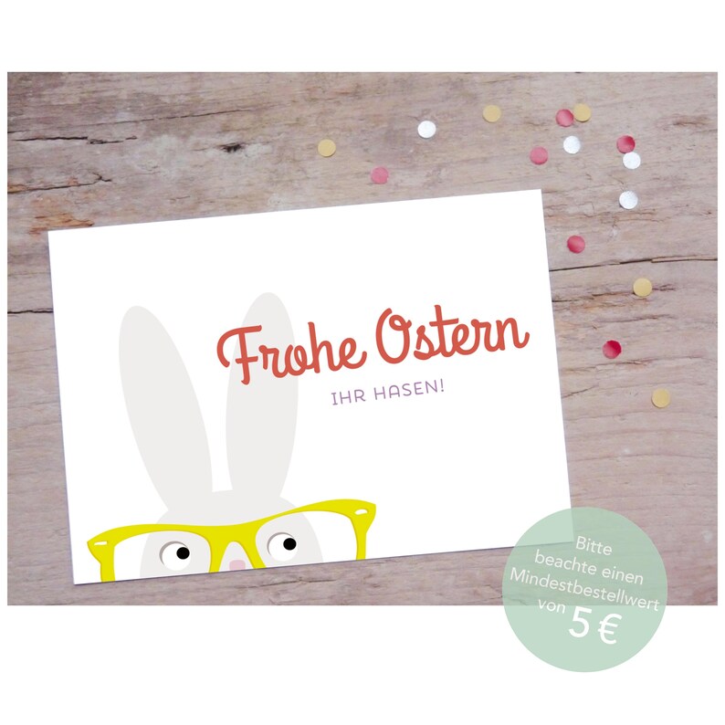 Peut inclure: Un lapin blanc portant des lunettes jaunes se cache derri&egrave;re une carte blanche. La carte est d&eacute;cor&eacute;e de l'inscription "Frohe Ostern" en rouge et "Ihr Hasen!" en noir. La carte a un fond vert clair avec une bordure blanche.