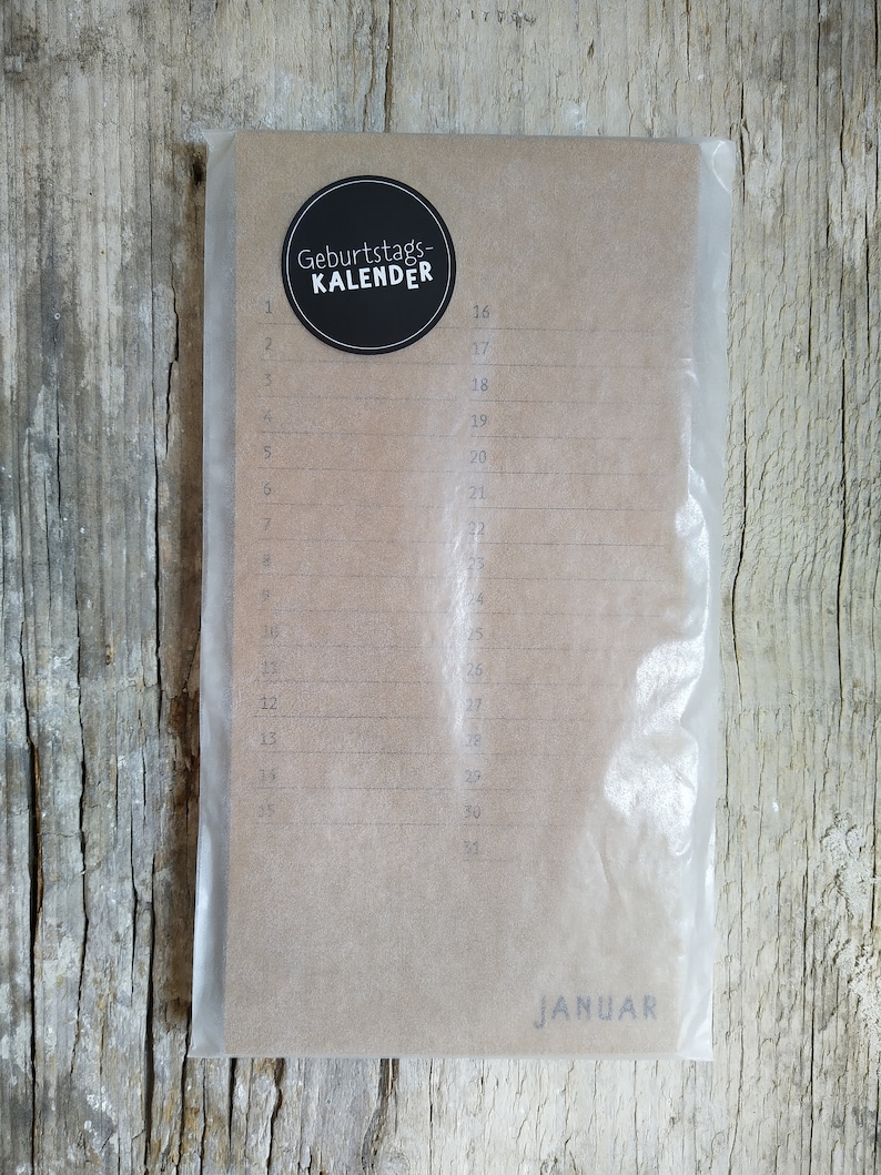 May include: A brown paper calendar with a black circle sticker that says "Geburtstags-KALENDER" and the month "JANUAR" printed at the bottom. The calendar has numbered days from 1 to 31.