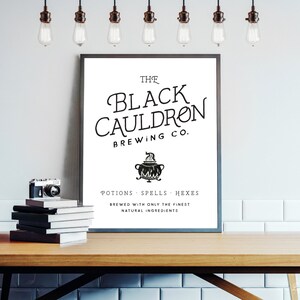 May include: A black and white poster with the text "The Black Cauldron Brewing Co." and a black cauldron with steam coming out of it. The text below the cauldron reads "Potions Spells Hexes Brewed with only the finest natural ingredients."