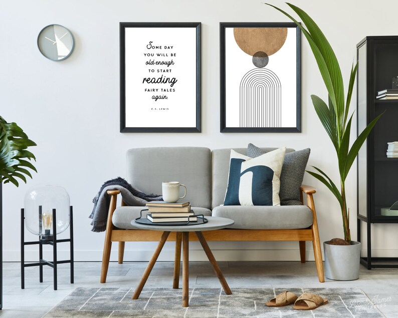 May include: A living room interior with a gray sofa, a round coffee table, a floor lamp, a potted plant, and two framed prints on the wall. The print on the left features a quote by C.S. Lewis: "Some day you will be old enough to start reading fairy tales again." The print on the right features a geometric design with a brown circle, a gray circle, and black lines.