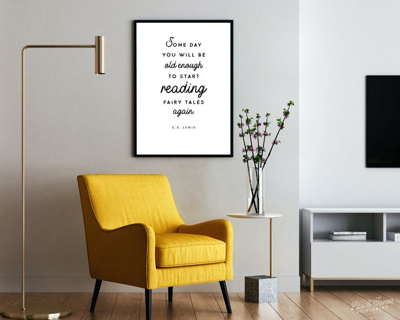 May include: A black and white framed print with a quote by C.S. Lewis that reads "Some day you will be old enough to start reading fairy tales again". The print is hanging on a white wall above a yellow armchair.