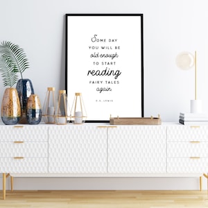 May include: A white framed print with a black and white quote by C.S. Lewis that reads "Some day you will be old enough to start reading fairy tales again." The print is hanging on a white wall above a white dresser with gold accents.