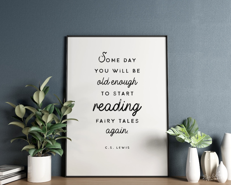 May include: Black and white typography print with the quote "Some day you will be old enough to start reading fairy tales again." by C.S. Lewis. The print is framed and displayed on a wall with a light blue background.