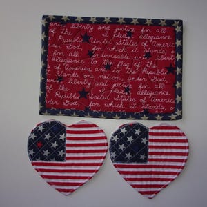 May include: A patriotic set featuring a red, white, and blue theme. Includes two heart-shaped coasters with American flag designs and a rectangular piece with the Pledge of Allegiance text.