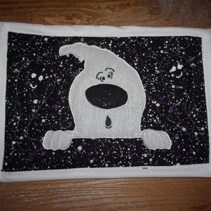 May include: A white ghost with a black nose and eyes peeking out from behind a black and white fabric with purple splatter. The fabric has a white border.