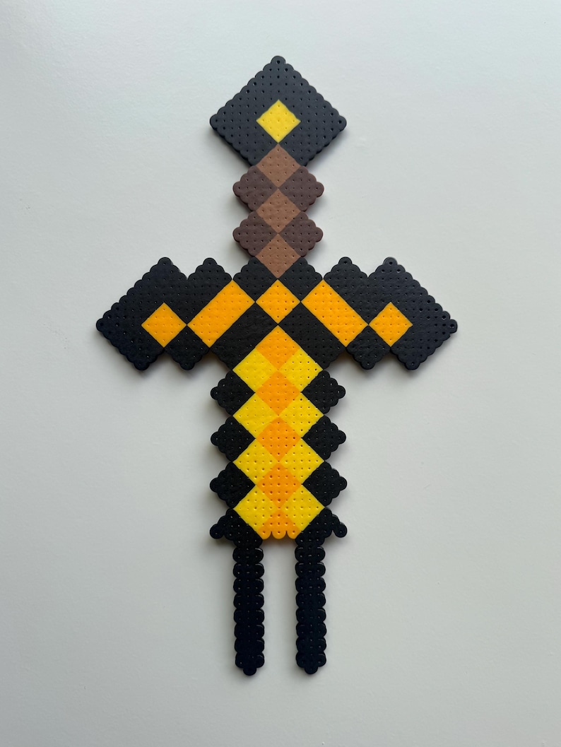 May include: A black, yellow and brown Minecraft sword made of perler beads.