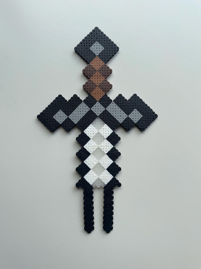 May include: A black and white pixel art sword made with perler beads. The sword has a brown handle and a grey blade.