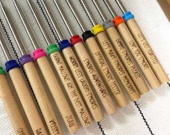 May include: A set of 12 wooden roasting sticks with colorful tips and personalized engravings. The engravings include names and fun phrases related to making s'mores.