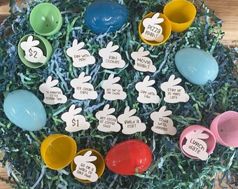 May include: A collection of plastic Easter eggs filled with white bunny-shaped paper slips, each with a different activity or treat written on it. The activities include "Pizza Night", "Movie Night", "Ice Cream Date", "Stay Up 30 Mins Late", "Lunch Date", "Go on a Walk or Bike Ride", "Build a Fort", "Hot Cocoa at Coffee Shop", "Set Out of One Chore", "Day with Dad", "Day with Mom", "15 Minutes Extra Screen Time", "Bake Cookies", "Soda with Dinner", and "$1" and "$2".