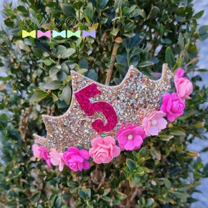 May include: Gold glitter crown with a pink felt number 5 and pink felt flowers. The crown is decorated with gold glitter and pink felt flowers.