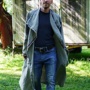 May include: A person wearing a long, light green coat with red trim, a black shirt, blue jeans, and black shoes. The person is walking on green grass. The image includes the text "DongoDesign".