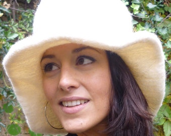 Puede incluir: Un sombrero crema de ala ancha con un aspecto suave y texturizado. El sombrero tiene una copa redondeada y un ala suavemente inclinada. La imagen también incluye el texto "DongoDesign" en la esquina inferior derecha.