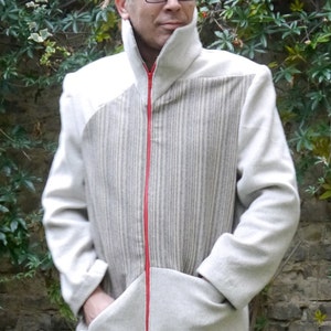 Könnte beinhalten: Eine weiße Jacke mit einem roten Reißverschluss und einem gestreiften Einsatz auf der Vorderseite. Die Jacke hat einen hohen Kragen und eine Tasche auf der Vorderseite. Die Jacke ist aus einem weichen, bequemen Stoff gefertigt.