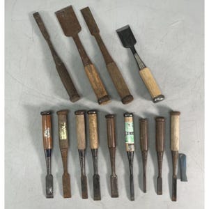 May include: A collection of twelve assorted woodworking chisels featuring metal blades and wooden handles of varying lengths and finishes. Some handles display metallic labels or green tape, while others show natural wood grain and signs of wear.