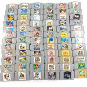 Puede incluir: Una colección de cartuchos de juegos grises de Nintendo 64. Las etiquetas de los juegos presentan ilustraciones coloridas de varios personajes y títulos de juegos. Los cartuchos están dispuestos en un patrón de cuadrícula, mostrando una variedad de videojuegos clásicos.
