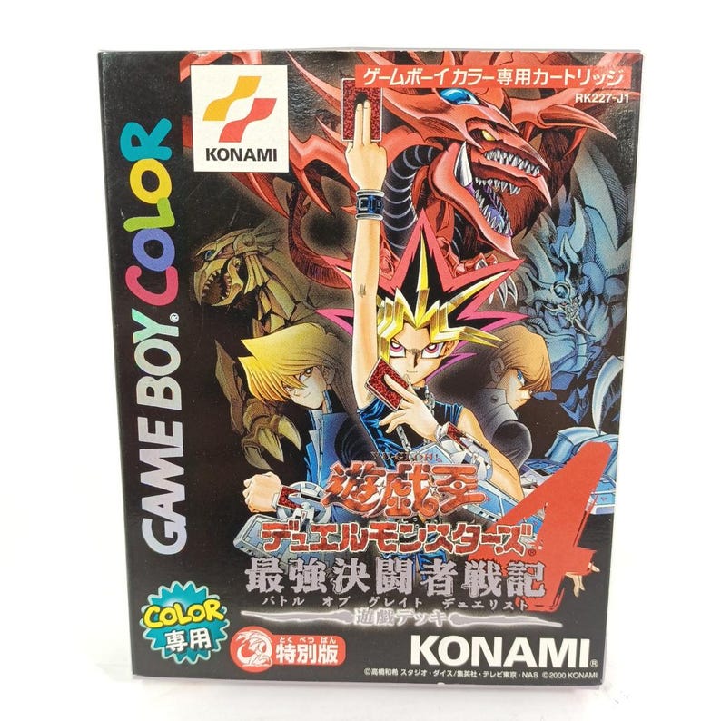May include: A black Game Boy Color video game cartridge box with a colourful illustration of characters and a red dragon. The box includes Japanese text and the Konami logo. The game title is "Yu-Gi-Oh! Duel Monsters 4".