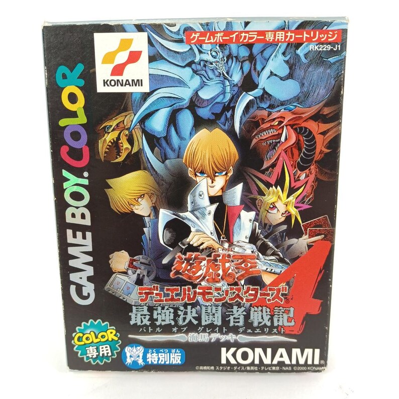 May include: A Game Boy Color video game cartridge box with illustrations of characters and monsters from Yu-Gi-Oh! Duel Monsters. The box is black with Japanese text and the Konami logo.