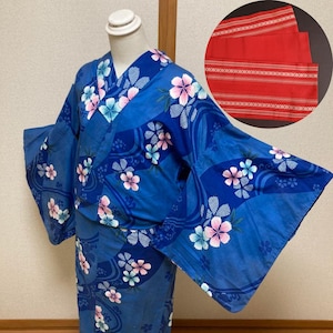 May include: A blue Yukata, a traditional Japanese garment, is displayed on a mannequin. The Yukata features a floral pattern in pink, white, and blue. A red obi belt with white stripes is shown in a circular inset.