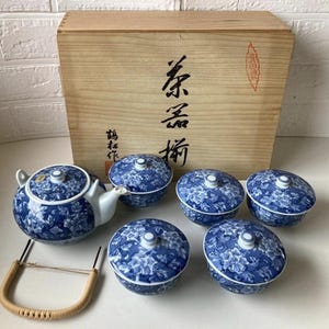 以下が含まれることがあります： 青と白の磁器のティーセット。ティーポットと蓋付きのカップ6個、花柄。セットには、日本語の文字とハンドルが付いた木箱が含まれています。