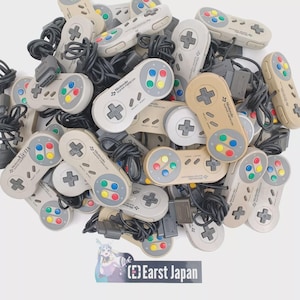 Może przedstawiać: Stos szarych i beżowych kontrolerów Super Nintendo Entertainment System z czarnymi kablami. Kontrolery mają różne kolorowe przyciski, w tym czerwony, zielony, niebieski i żółty. Kontrolery są oznaczone "Nintendo Super Famicom" w języku japońskim.