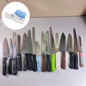 May include: Collection of various kitchen knives with black, green, and wooden handles. The knives are of different sizes and blade styles, including serrated and smooth edges. A white knife sharpener with blue accents is in the upper left corner.
