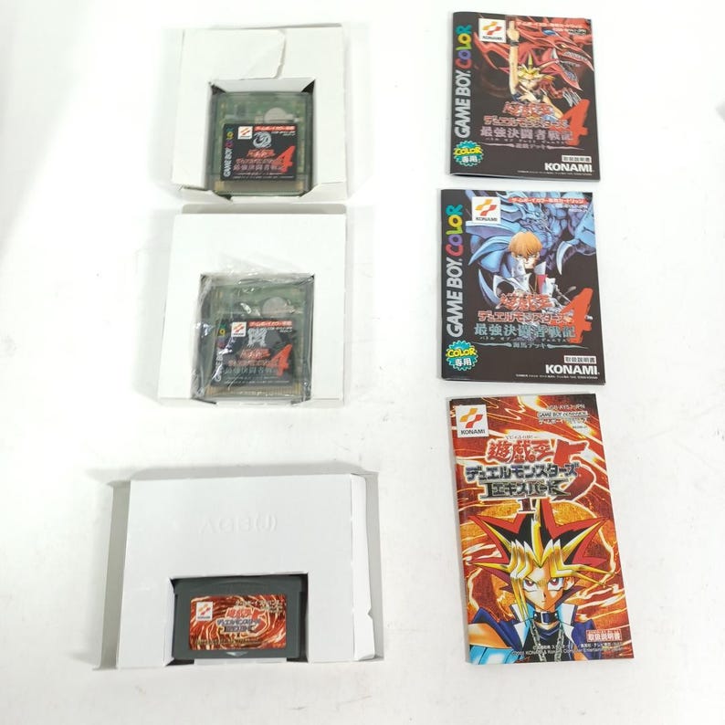 May include: Three Game Boy Color video game cartridges and their boxes. The cartridges are in white cardboard packaging. Three game boxes are visible, each with Japanese text and colourful illustrations of characters.