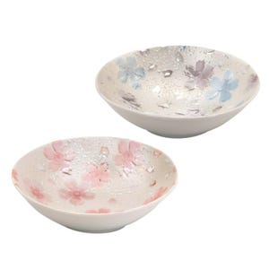May include: Two white ceramic bowls with floral designs. One bowl features pink flowers, the other has blue and purple flowers. The interior of the bowls have a textured, droplet-like pattern.
