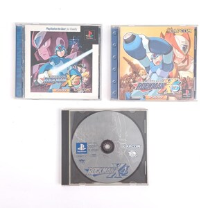 Puede incluir: Tres cajas de juegos de video para la consola PlayStation. Las cajas son azules, amarillas y negras. La parte frontal de las cajas presenta al personaje de videojuego Mega Man. El texto en las cajas dice "Rockman X6" y "Rockman X4".