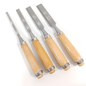 May include: Four wood chisels with silver blades and light brown wooden handles. The blades are labeled with sizes: 6mm, 12mm, 18mm, and 21mm. Each chisel has a silver metal band at the base of the handle.