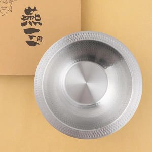 May include: A stainless steel bowl with a hammered texture around the rim and a smooth, reflective interior. The bowl is set against a light brown background, with Japanese text and a map of Japan visible on a cardboard box.